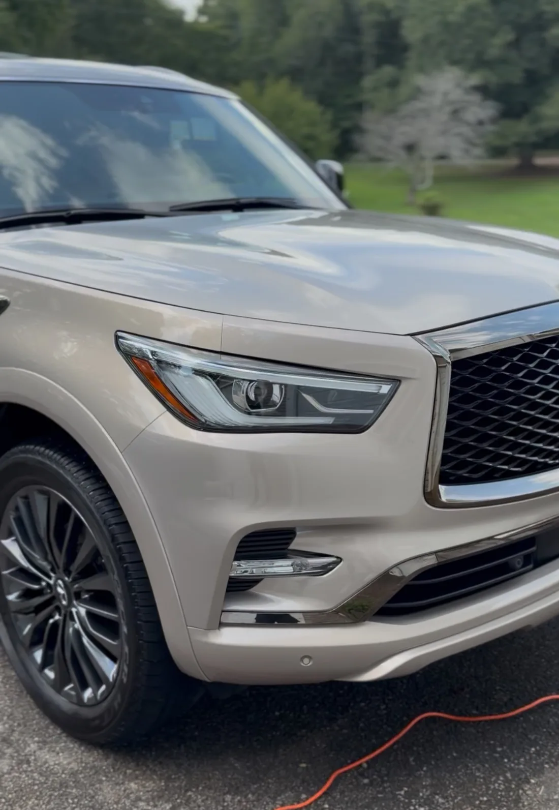 Champagne Infiniti QX80 freshly detailed in a customer's driveway