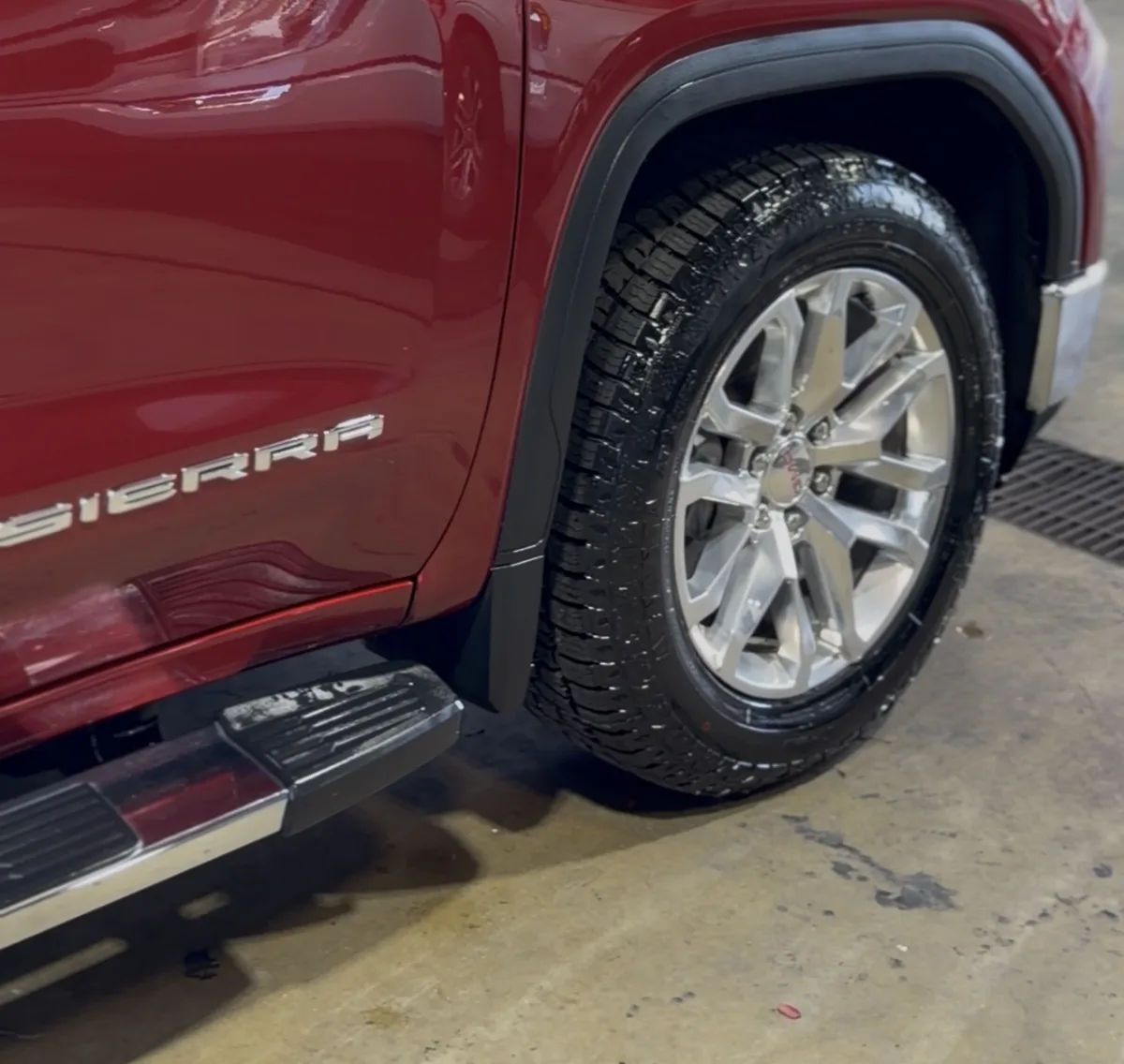 Close-up of a red GMC Sierra's dressed tire and gleaming lower panel after a wash