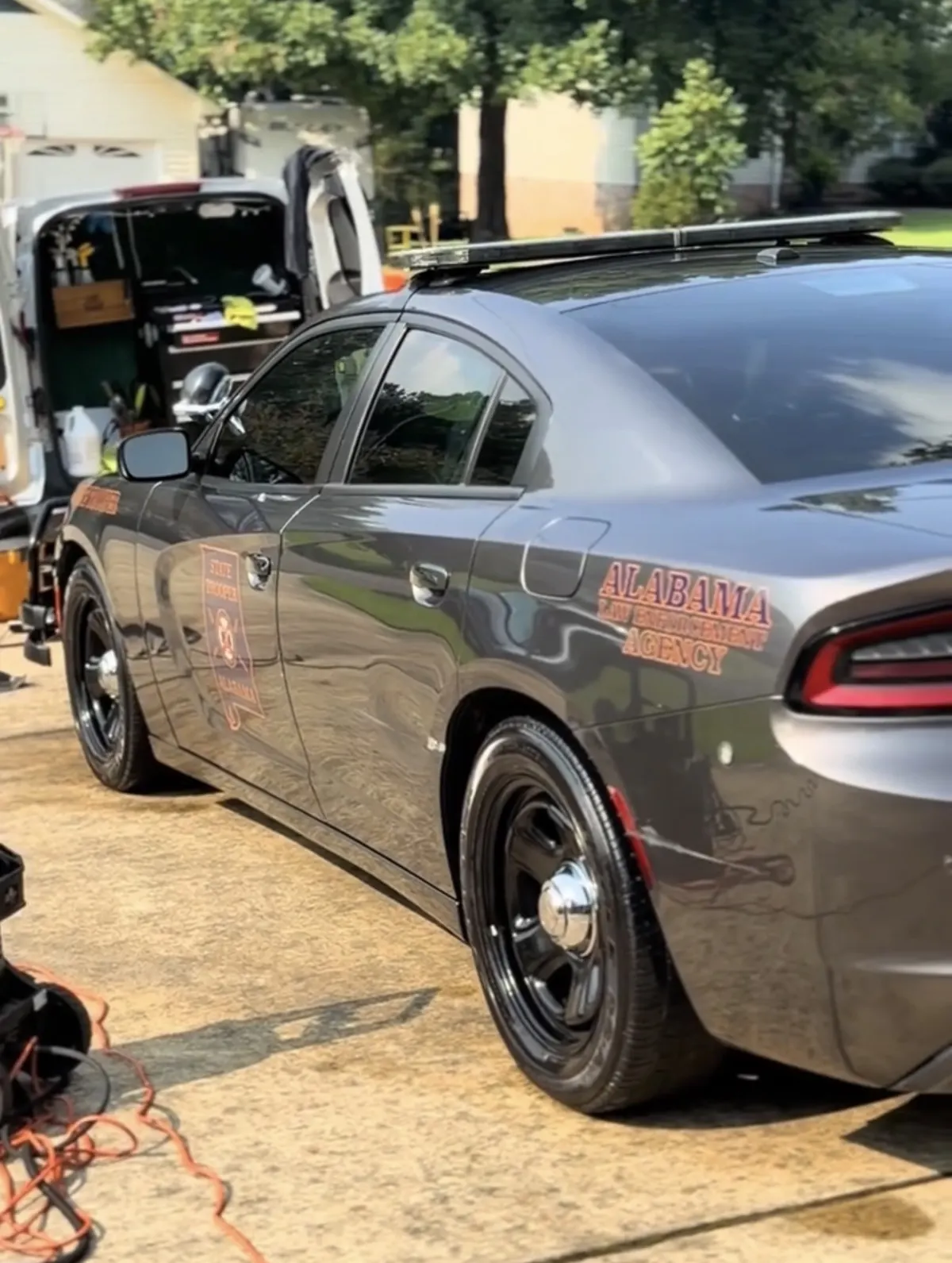 Alabama state trooper Charger gleaming beside Daniel's fully equipped mobile detailing rig
